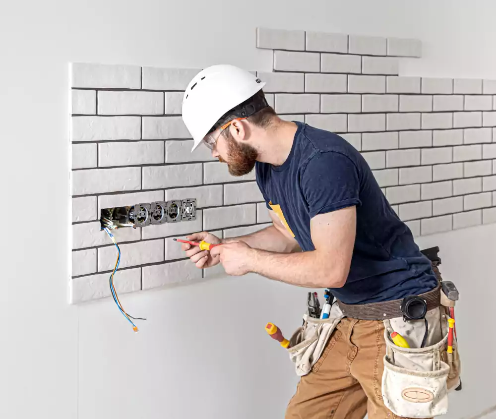 electrician construction worker with beard overalls during installation sockets home renovation concept