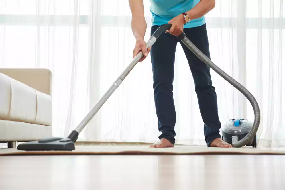 lower body shot unrecognizable man vacuuming carpet home